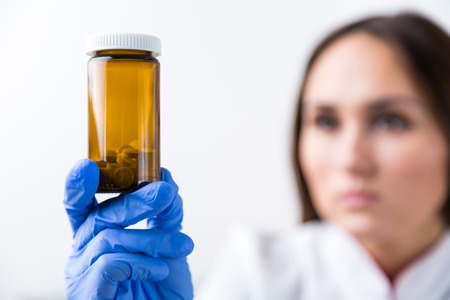 Doctor with hand in medical glove holding pill box, blurred look. Concept of medical help.の写真素材