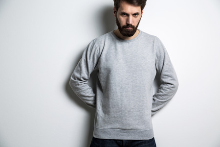 Serious man in long sleeved sweatshirt on light grey backgroundの写真素材