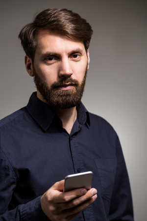 Businessman looking at the camera with smartphone in handsの写真素材
