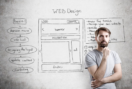 Bearded male with web design plan on concrete wall in the backgroundの写真素材
