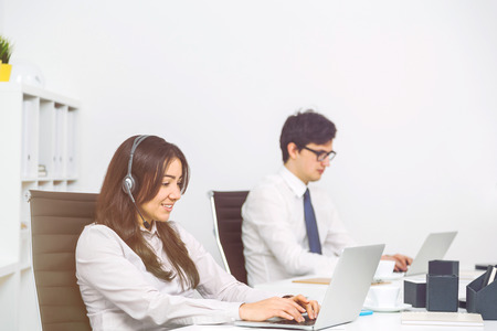 Sideview of businessman and businesswoman with headset working in officeの写真素材