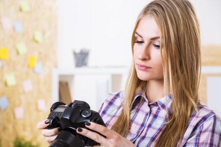Businesswoman holding black camera on office backgroundの写真素材