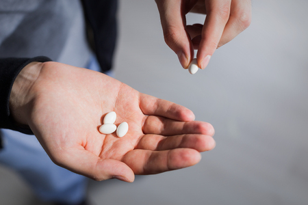 Male taking small pill from his palmの写真素材