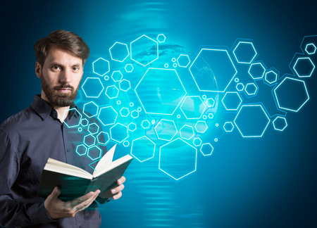 Bearded caucasian businessman with book standing next to digital pattern on blue background