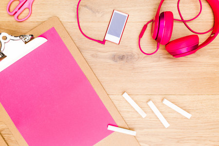 Top view of clipboard with pink paper sheet, white chalk sticks and smartphone with headphones. Mock upの写真素材