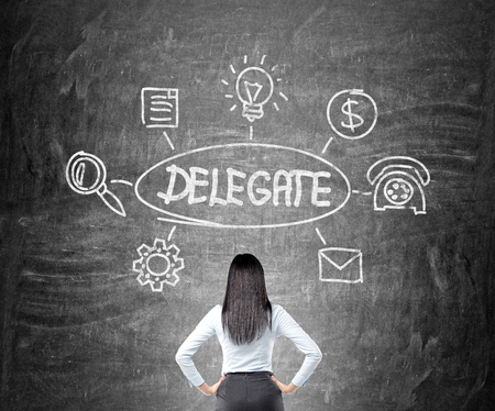 Businesswoman looking at delegating sketch on chalkboardの写真素材