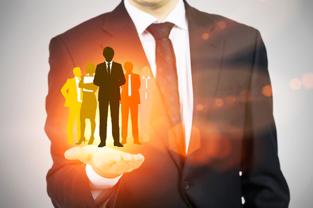 Human resources concept with man in suit holding bright orange businesspeople silhouettesの写真素材