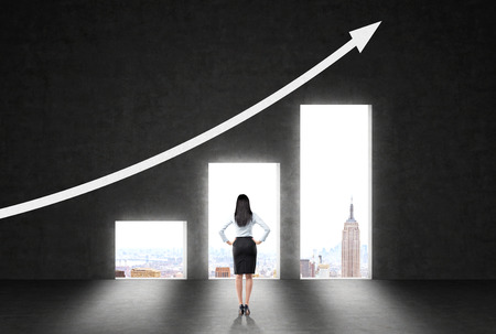 Success concept with businesswoman standing against wall with business chart, arrow and New York city viewの写真素材