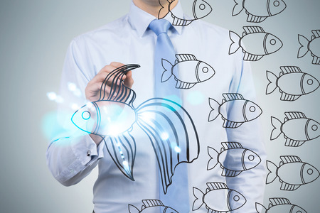 Different direction concept with businessman on grey background drawing abstract fish sketchの写真素材