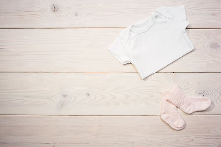 Baby shirt and socks on light wooden table. Mock upの写真素材