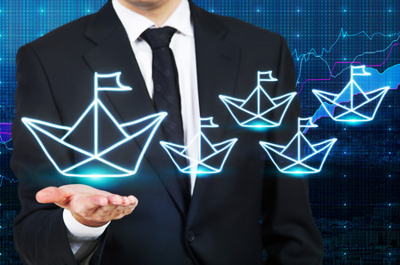 Leadership concept with fund manager holding big paper ship icon on forex chart backgroundの写真素材