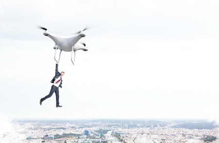 Businessman flying with quadrocopter over misty cityの写真素材