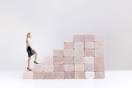 Success concept with businesswoman climbing wooden block stairs on white backgroundの写真素材