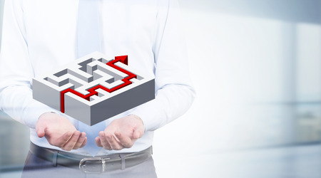 Solution concept with businessman holding abstarct maze with red arrow going through it on blurry backgroundの写真素材