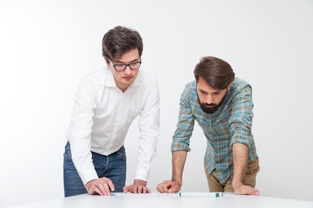 Man and his coworker looking at blueprints on white desk. Concept of engineering workの写真素材