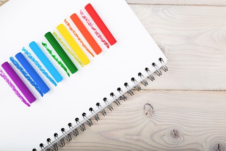 Lines of rainbow colors. Lines drawn with chalks of different colors on sheet of paper in notebook. Concept of creativity freedom. Close up. Top viewの写真素材