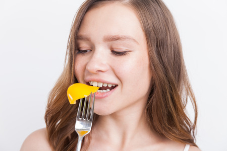 Young girl biting yellow bell pepper and enjoying good diet. Concept of dieting. Organic fitness
