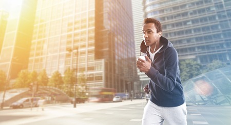 African American man jogging in business district in London at morning time. Concept of healthy way of life importance. Toned imageの写真素材