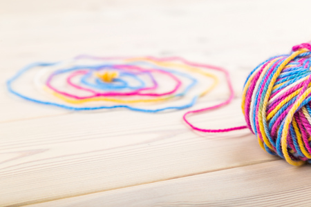 Large bundle of wool lie on wooden table with its thread curled in spiral. Concept of hobby and free...