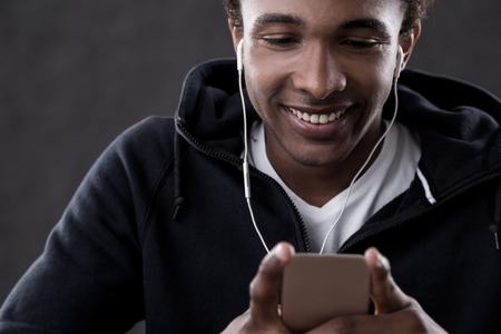 Smiling African American man with headphones listening to music on his phone. Concept of relaxation