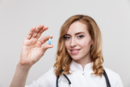 Gorgeous woman doctor with stethoscope and blue pill. Concept of impotence and man's reproductive healthの写真素材