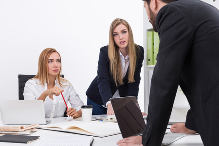 Business lady and her assistant look at their colleague not pleased with his results. Concept of matriarchy in officeの写真素材