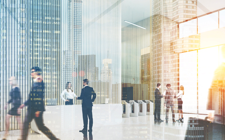 Busy office lobby. Man and woman are shaking hands. Their colleagues are discussing future board meeting. Concept of large company office. Toned image, double exposureの写真素材