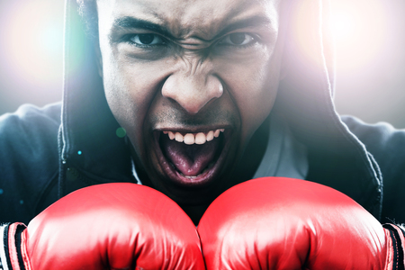 Close up of enraged African American man in boxing gloves. Concept of championshipの写真素材