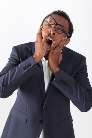 Close up of stressed out African American man with lopsided glasses screaming in despair. Concept of stressful workの写真素材