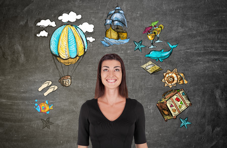 Smiling girl standing against blackboard with sketches. Concept of fictional worlds and passed timeの写真素材