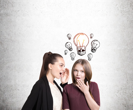 Portrait of two girlfriends gossiping. One of them is surprised and has an idea. Concept of intrigues and plot twists in our livesの写真素材