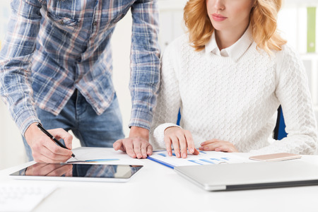 Close up of man in casual clothes and woman working together at table and reading a report. Concept of communicationの写真素材