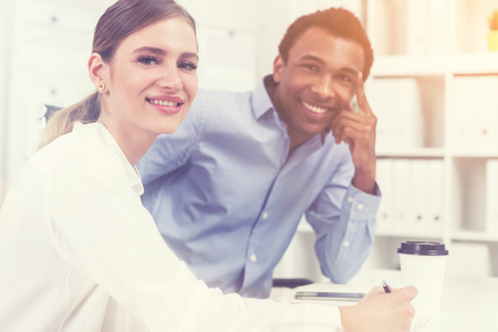 Man and woman sitting at desk and smiling to camera. Concept of good team working as a team. Toned imageの写真素材