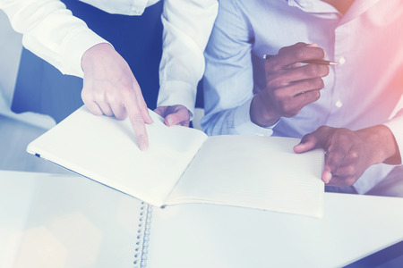 Businesswoman showing man his notes. He is holding notebook and listening. Concept of working together. Toned imageの写真素材