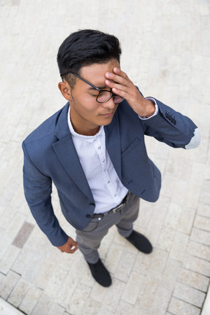 Close up of Asian man in elegant suit who is having a terrible headache. Concept of concentration and stress.の写真素材