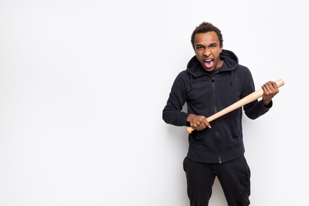 Angry African American guy holding a baseball bat and shouting. Concept of anger management. Mock upの写真素材