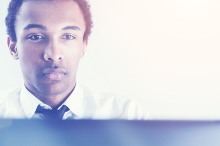 Portrait of handsome focused african american guy using laptop on white background. Toned image