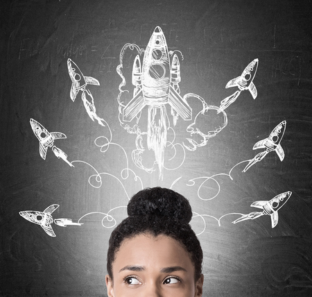 Close up of African American woman's head with large rocket flying above it and many smaller ones heading to different directions. Concept of project launchの写真素材