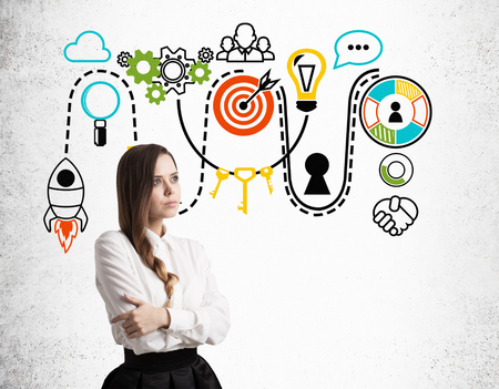 Pensive girl with braided hair is standing near concrete wall with colorful startup icons. Concept of startup foundationの写真素材