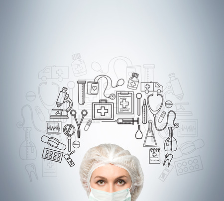 Close up of woman doctor's head standing against gray wall with medicine sketches on it. Concept of health careの写真素材