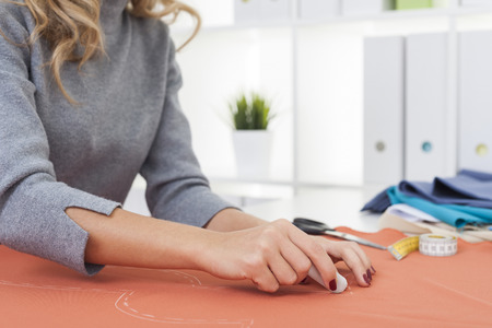 Close up of woman's hands with red nail polish who is drawing a pattern on a piece of tissue....