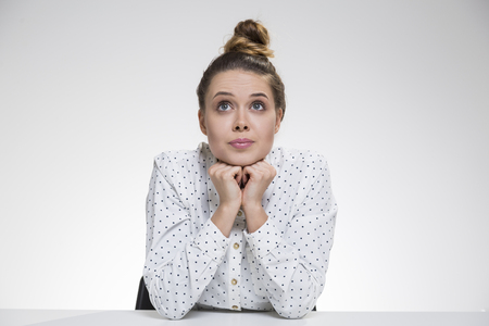 Dreamy girl in polka shirt is daydreaming with eyes wide open and her chin on her hands. Concept of dreaming. Mock upの写真素材