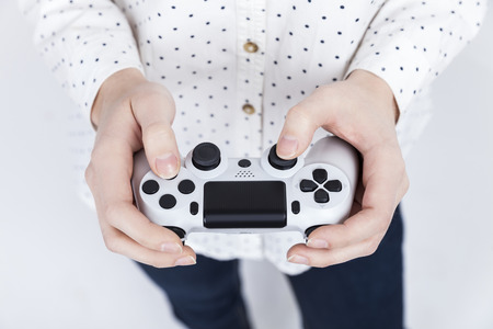 Close up of a girl in white polka dot shirt holding a video game controller with both hands. Concept...