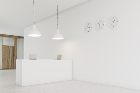 Office counter is standing in a lobby with three clocks on white wall. Wooden door is seen in the background. 3d rendering. Mock upの写真素材