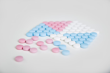 Tablets of different colors forming a hexagon on a whtie table surface. Concept of medicine and taking care of one's healthの写真素材