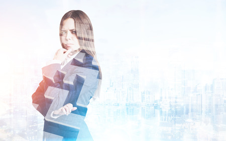Portrait of a frowning young businesswoman in a suit who is standing against a city panorama. There is a maze in the foreground. Mock up. Toned image. Double exposureの写真素材