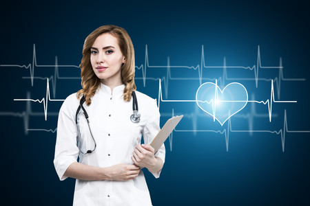Attractive female doctor with heartbeat chart and clipboard in hand. Medicine and health conceptの写真素材