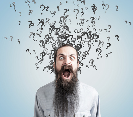 Close up of a businessman with a long beard screaming while question marks are emerging from his head.の写真素材