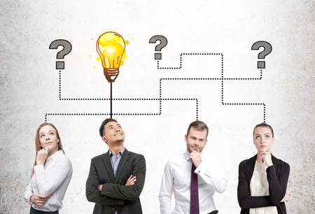 People are standing near a concrete wall and brainstorming. They are looking for the answers. One guy have found the solution.の写真素材