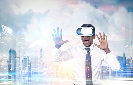 Portrait of an African American businessman wearing vr glasses and standing in city. He looks amazed...